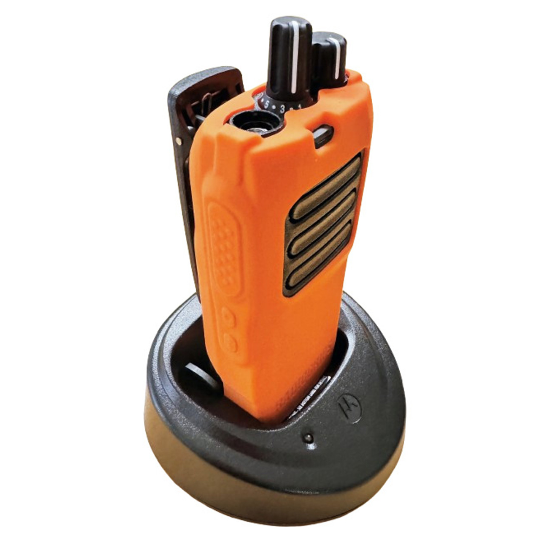 Motorola R2 radio in a charging dock while fitted with the RadioGrips® Orange Silicone Carry Case, demonstrating its compatibility with charging stations.
