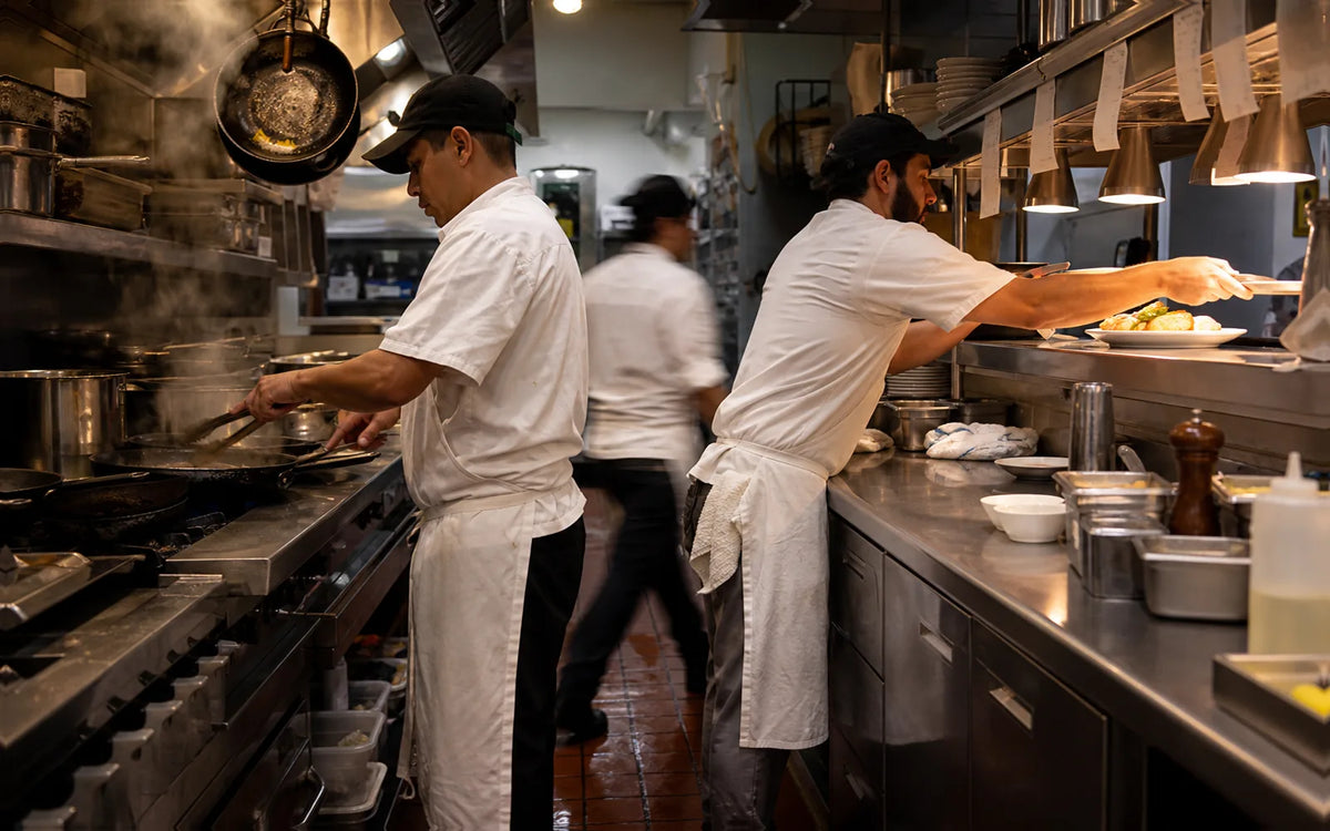 Line cooks preparing and plating meals in a busy United States commercial restaurant kitchen