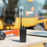 Motorola CP100d two-way radio on a construction site workbench with tools, ideal for reliable jobsite communication.